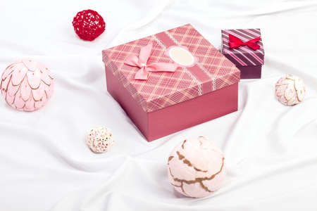 Two gift boxes on white satin background with ball decorationsの写真素材