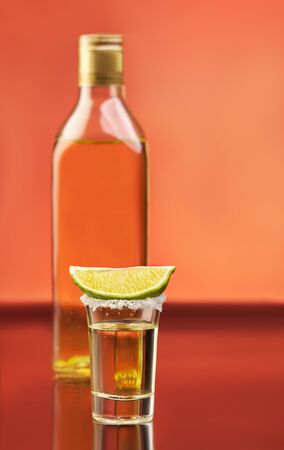 Tequila bottle with full glass and slice of lime with salt above. Traditional mexican alcohol drinksの写真素材