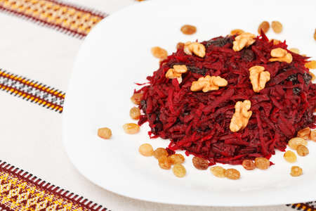 Grated beet salad with prunes, raisins and walnut served on a white plate and home tablecloth. low aperture shot, selective focusの写真素材