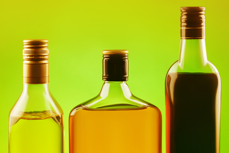 Elite alcoholic drinks on green background with sunlit effect. Three different bottles setの写真素材