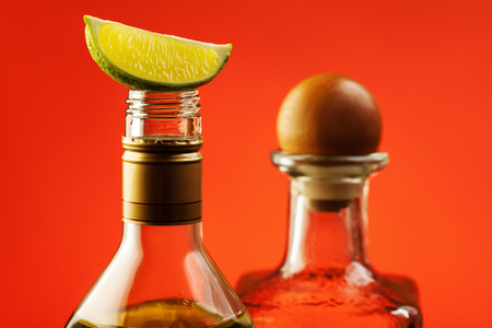 Slice of lime on the top of tequila bottle with another bottle with wooden cork on background.の写真素材