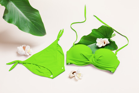 Green swimwear (bra and panties) set with sea shells, flowers, palm leaves. Summer travel fashion composition.の写真素材