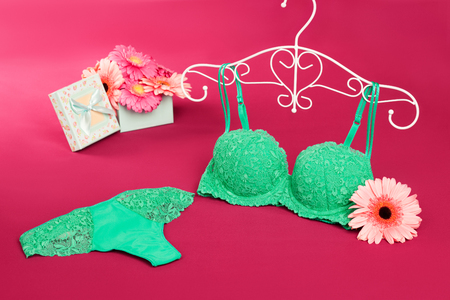 Panties and bra on a hanger and gerberas with gift box in the backgroundの写真素材