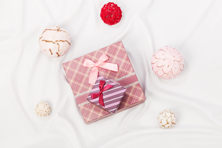 Two decorated with ribbons gift boxes on white silk canvas with decorative balls around. Low aperture, focus on top small boxの写真素材