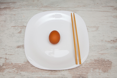 egg with chopsticks on a plate at wooden backgroundの写真素材