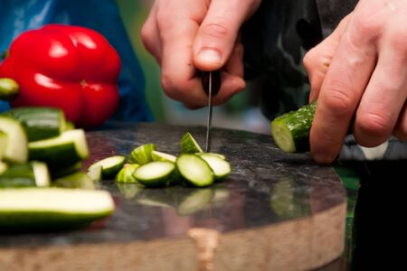 man cutting vegetables for salad by knifeの写真素材