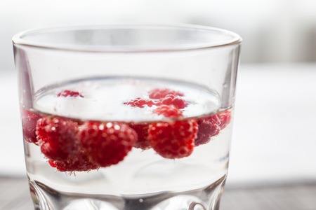 Sparkling raspberry lemonade water in a transparent glassの写真素材