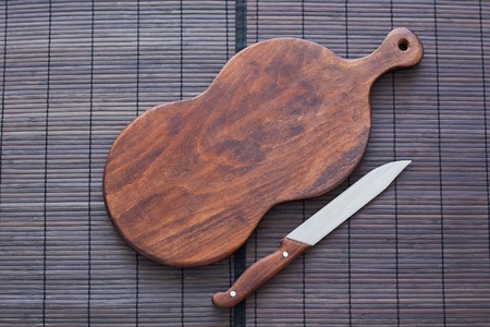 A view looking down on a piece of garlic next to a large knife on a worn butcher block cutting board.の写真素材