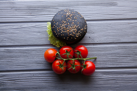 Fast food black hamburger with cherry tomatoes on a gray backgroundの写真素材