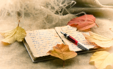 Old notebook and fountain pen on the autumn leavesの写真素材
