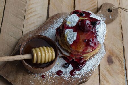 Pancake on a wooden board with honey and powdered sugarの写真素材