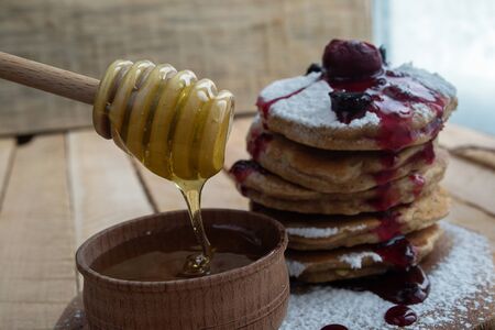 Pancake on a wooden board with honey and powdered sugarの写真素材