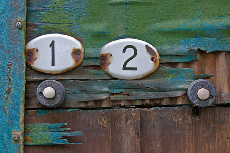 Enameled metal plates with the numbers of apartments on the old wooden doorの写真素材