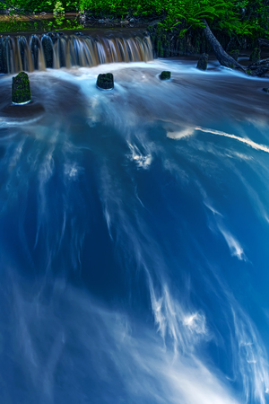 Rotated sky and a creek with a waterfall, united in a collage.の写真素材