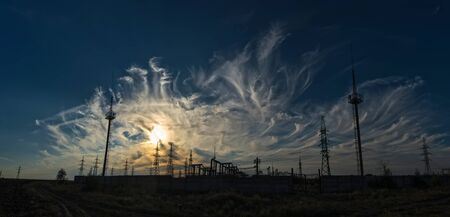 Support and wires of the power plant on the background of spectacular sunset clouds
