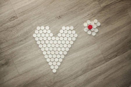 Heart shape solidary made with recycled plastic caps on a wooden floorの写真素材