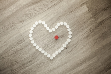 Heart shape solidary made with recycled plastic caps on a wooden floorの写真素材