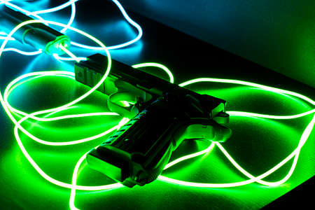 Black pistol with green and blue neon cablesの写真素材