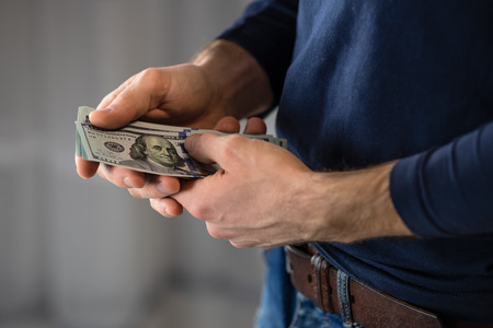 Male hand with money. One hundred dollar bills.