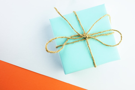 Gift of blue color tied with twine on a white-orange background, top view, minimal styled.の写真素材
