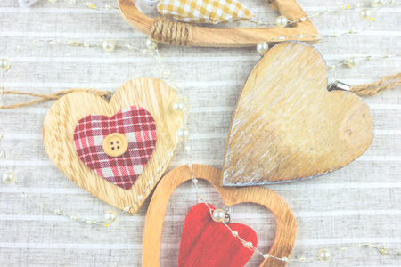 Fabric background with many different decorative hearts on wood .