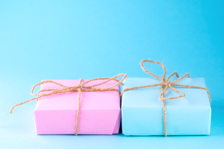Two gift boxes of pink and blue on a blue background, minimalism photography. Place for text.の写真素材