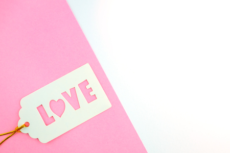 White gift tag with inscription love, on a pink and white background . Place for text.の写真素材