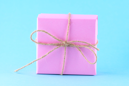 Pink gift box tied with string on a bright blue background, minimalism, parcel, place for text.の写真素材