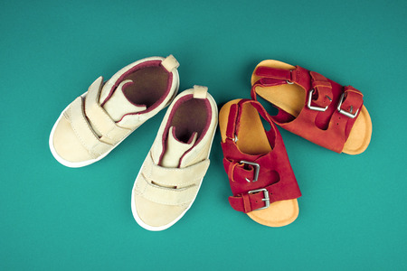Sneakers and sandals on a green background, top view, summer shoes. Flat lay.の写真素材