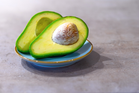 Half avocado with bone on gray kitchen countertop. The concept of healthy eating. Place for text.の写真素材