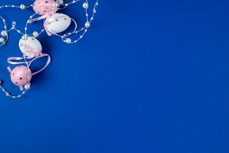 Easter egg decorated with ribbons and pearls on a blue background. Place for text.の写真素材
