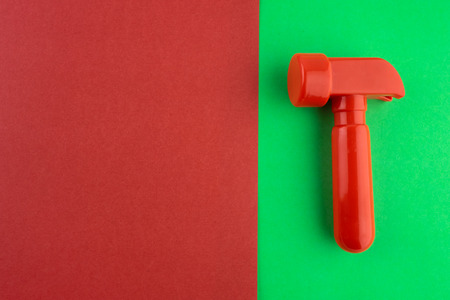 Toy red hammer r on a red-green paper background.の写真素材
