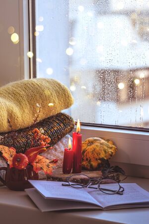 Autumn composition on a windowsill reading a book on a rainy evening.の写真素材