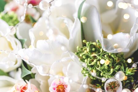 Beautiful bouquet of white tulips with green leaves and other decorative flowers close up.の写真素材