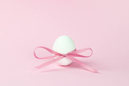 close-up Easter egg decorated with a pink bow on a pink background, festive minimalism. Holiday concept. Keto diet, a healthy food product.の写真素材