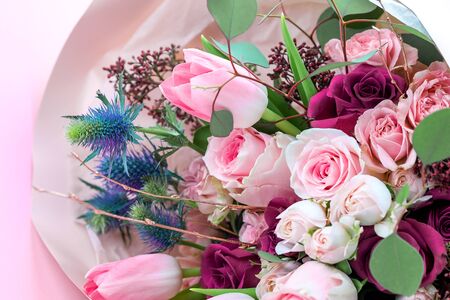 A closeup bouquet of roses and tulips decorated with leaves and twigs of other beautiful plants. Holiday concept. Flowers for Mother's Day. Copy space.の写真素材