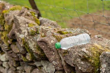 empty discarded water bottle on a dry stone wall, environmental issues