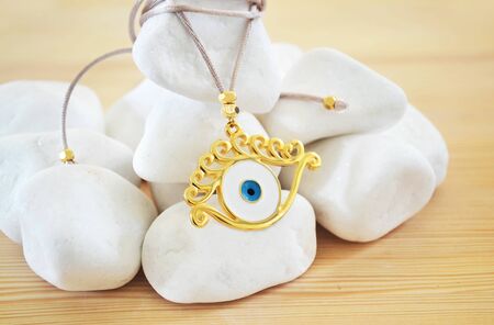 evil eye necklace on white stones and wooden backgroundの写真素材
