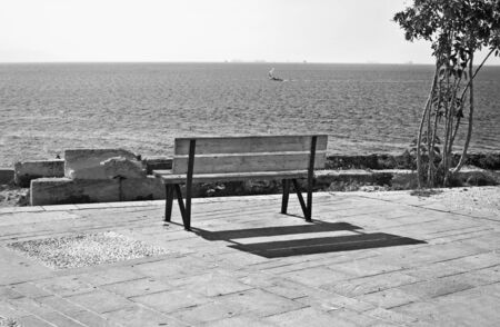 black and white photography Piraiki Piraeus Greece - park bench in front of the seaの写真素材