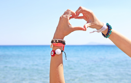 greek jewelry advertisement on the beach - heart symbol with handsの写真素材