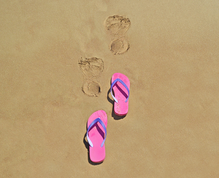 summer flip flops on the beach with footsteps on sand - summer vacation iconの写真素材