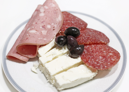 plate with cold cuts - salami and ham - olive oils and the white greek cheese called fetaの写真素材