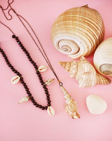 still life of shell necklaces on pink background - summer jewelry with shells