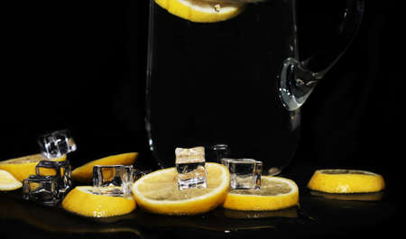 still life of wet lemons with ice on black background