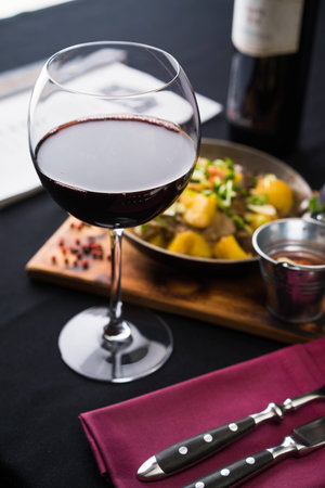 glass of red wine in front of freshly cooked meatの写真素材