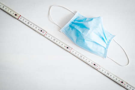 Safe workplace concept, surgical mask and folding wooden meter are placed on a white background,...
