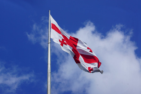 Georgian flag on blue sky backgroundの写真素材