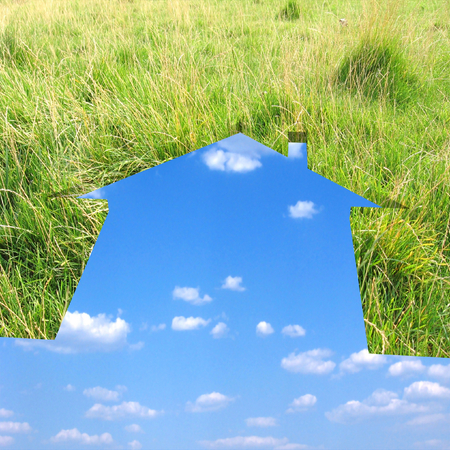 Eco house metaphor. House with grass, sky and clouds.の写真素材