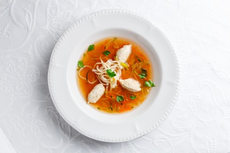 Tasty chicken soup with noodles and vegetables in white bowlの写真素材