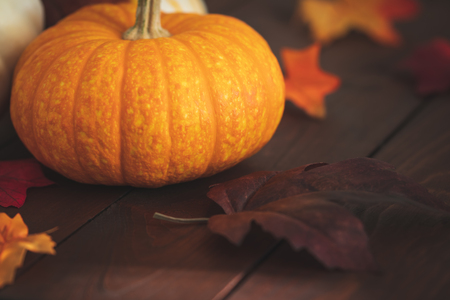Pumpkin with fall foliage on a dark brown table.の写真素材
